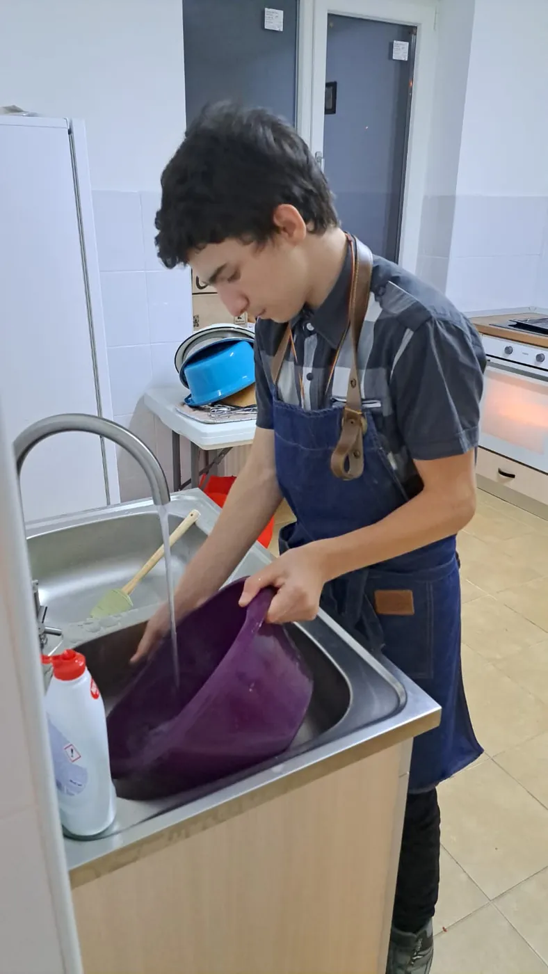 Copil spălând vasele la atelierul de menaj