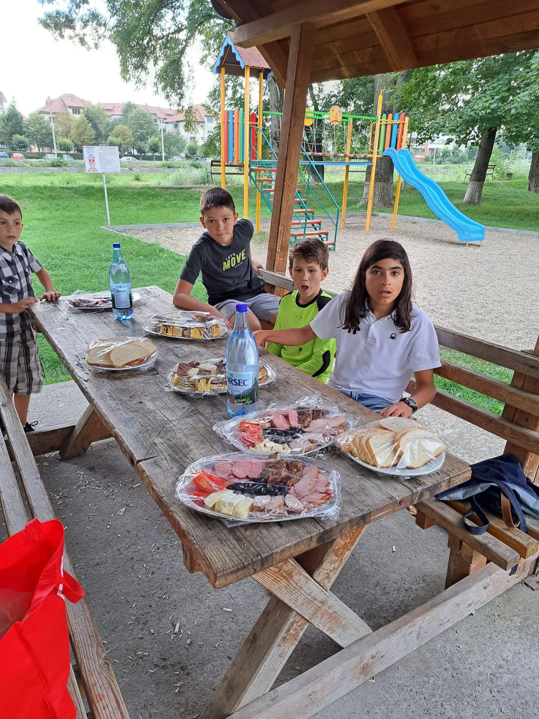 Copii la masa de picnic în parc, în timpul atelierelor de vacanță